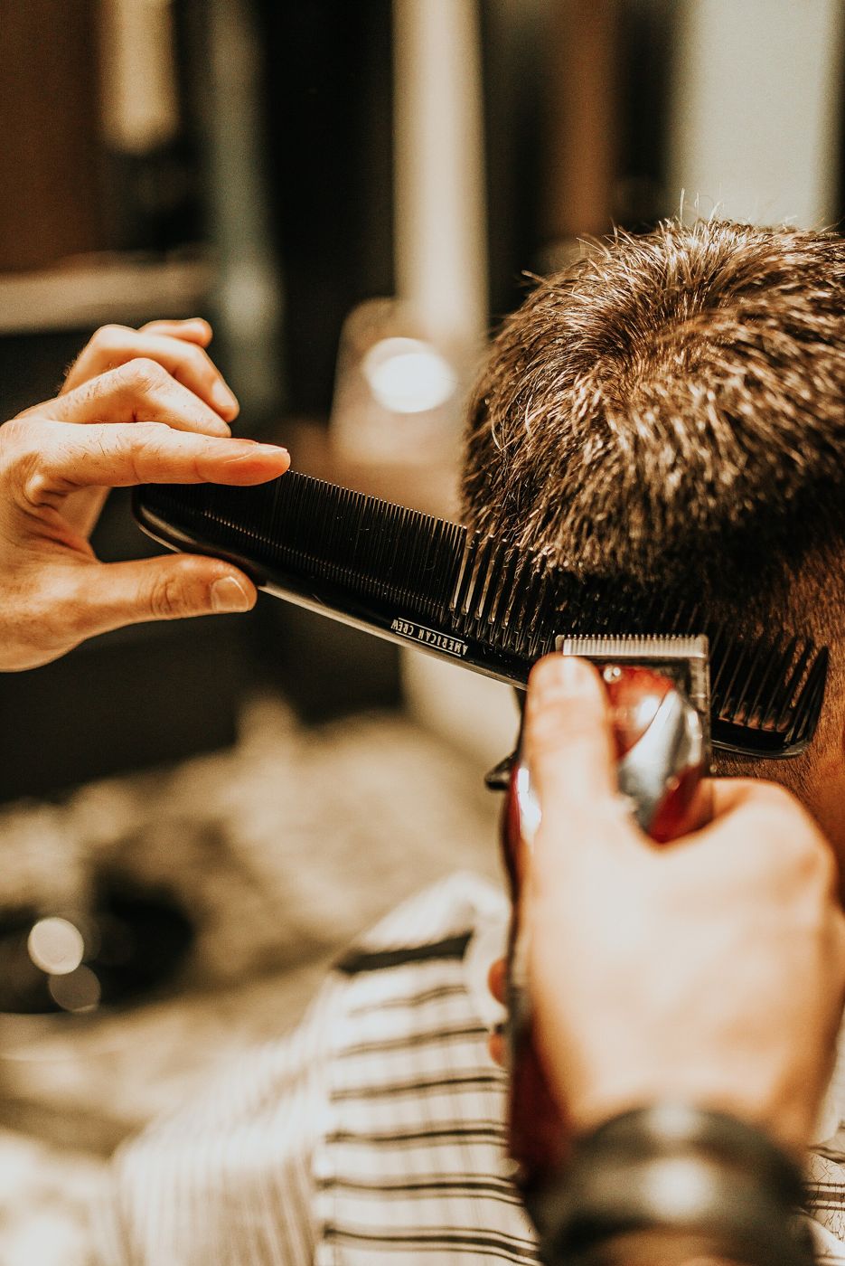 Barbeiro acertando o corte com pente e máquina