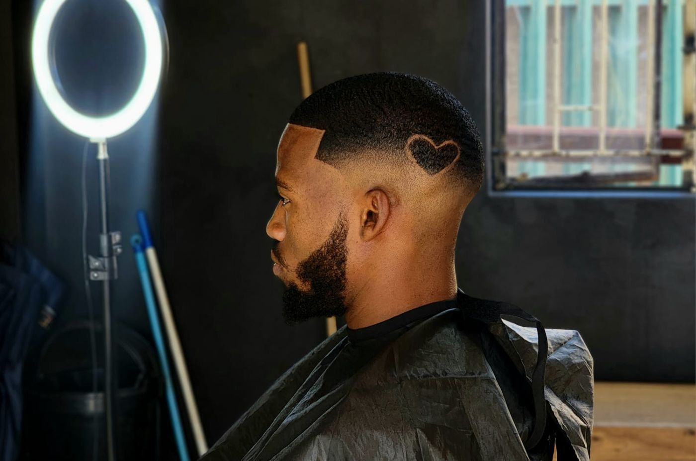 Cliente com barba feita e degradê sob luz de anel